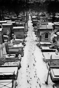 Fotografía de unas huellas sobre la nieve en el paseo de un cementerio.