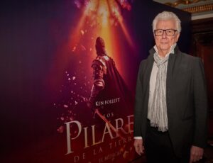 Ken Follett frente al poster de la adaptación de su obra Los Pilares de la Tierra
